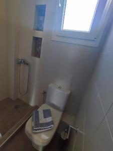 uma casa de banho branca com um WC e uma janela em A & F Apartments - Fay's house em Kalivia Poligirou