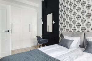 1 dormitorio con cama y pared con espejo en Manpro Apartments Toruń en Toruń