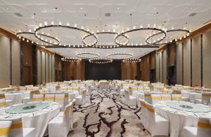 un gran salón de banquetes con mesas y sillas blancas en Courtyard by Marriott Xinchang en Xinchang