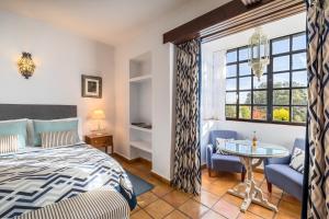 a bedroom with a bed and a table and a window at La Bobadilla, a Royal Hideaway Hotel in Villanueva de Tapia