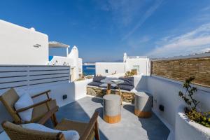 Un balcón con sillas y una mesa y el océano. en Mykonos Perla Town House, en Mykonos ciudad
