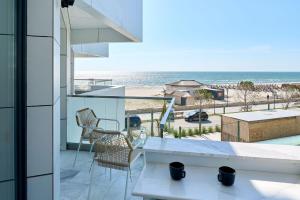 balcón con mesa y sillas y la playa en Infinity Everglow Apartment Spa&Pool Beach Resort-parking, en Mamaia