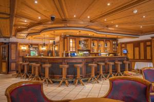 a bar in a restaurant with wooden ceilings and wooden stools at MANNI das Hotel in Mayrhofen