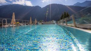 a large swimming pool with mountains in the background at MANNI das Hotel in Mayrhofen