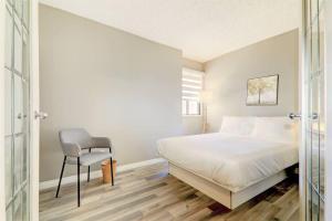 a white bedroom with a bed and a chair at Roomy Top Floor at Stampede w Free Parking and AC in Calgary