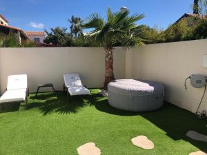 a backyard with a hot tub and two chairs at Villa Agde très calme in Agde