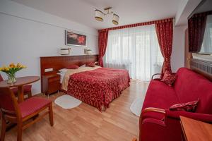 um quarto com uma cama vermelha, uma mesa e cadeiras em Aquapark Health Resort & Medical SPA Panorama Morska All Inclusive em Jarosławiec