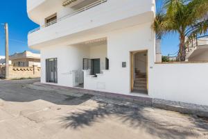 una casa blanca con una palmera delante de ella en Mare del Salento Residence by BarbarHouse, en Torre Lapillo