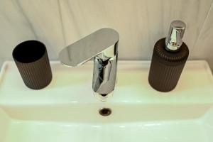 a bathroom sink with a faucet and two cups at Thessaloniki Center Modern Apartment in Thessaloniki