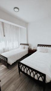 two beds in a room with white walls and wooden floors at Piso BOIRO PLAYA Robustiano in Boiro