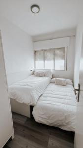 two beds in a room with white walls and a window at Piso BOIRO PLAYA Robustiano in Boiro