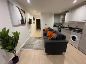 a living room with a black couch and a kitchen at 1-Bedroom Apartments in the Heart of Central Woking in Woking