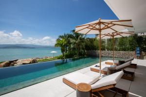 una piscina con 2 sillas y una sombrilla en Kerem Luxury Beachfront Villas en Nathon Bay
