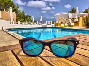 un par de gafas de sol sentadas en una mesa junto a una piscina en Hacienda Encanto del Rio en Es Figueral Beach