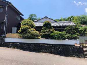 uma casa com uma parede de retenção branca com árvores em ゲストハウス Rei em Hongu