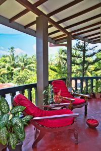 a porch with red chairs and plants on a balcony at Sri Lancashire Guest House in Bentota