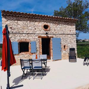 una mesa y sillas frente a un edificio de piedra en Le Cabanon des Lavandes entre Mont Ventoux et Luberon, en Sault-de-Vaucluse