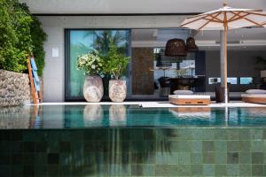 una piscina con 2 jarrones y una sombrilla en Kerem Luxury Beachfront Villas, en Nathon Bay