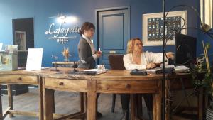une femme assise à une table avec un garçon debout à un bureau dans l'établissement Logis Hôtel Lafayette Rochefort France, à Rochefort