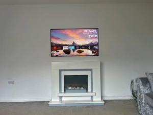 a flat screen tv above a fireplace in a living room at Remarkable 3-Bed House in Wirral in Wirral