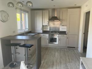 a kitchen with white cabinets and a island with bar stools at Remarkable 3-Bed House in Wirral in Wirral