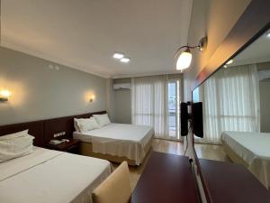 a hotel room with two beds and a tv at Admiral Hotel in Kizkalesi +25 photos