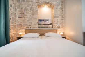 um quarto com uma cama e uma parede de pedra em Tifani Luxury Rooms 2 em Split