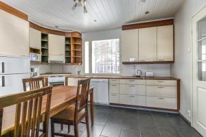 a kitchen with white cabinets and a wooden table at Lomahuoneistot Pajunkissa A ja B in Kalajoki