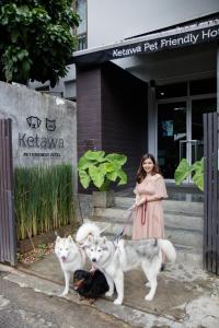 a woman in a dress with two dogs and twocats at Ketawa Pet Friendly Hotel in Chiang Mai