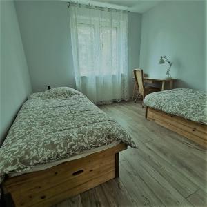 a bedroom with two beds and a desk and a window at Apartament Przy Parku w Orłowie in Gdynia