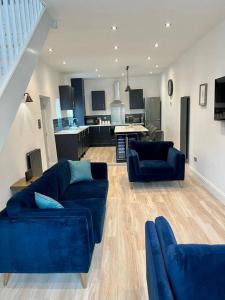 a living room with two blue couches and a kitchen at Stunning modern 2 bedroom, 2 bathroom townhouse in Cheltenham