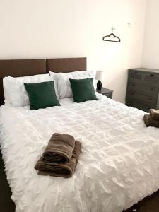 a white bed with green pillows and towels on it at Stunning modern 2 bedroom, 2 bathroom townhouse in Cheltenham