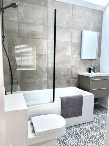 a bathroom with a tub and a toilet and a shower at Stunning modern 2 bedroom, 2 bathroom townhouse in Cheltenham