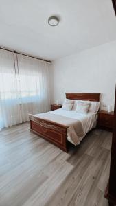 a bedroom with a large bed and a wooden floor at Piso BOIRO PLAYA Robustiano in Boiro