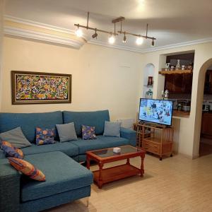 un soggiorno con un divano blu e una TV di Chalet de 8 camas a Orihuela Costa