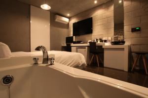 a bathroom with a tub with a bed and a television at Hotel Pop2 Jongno in Seoul