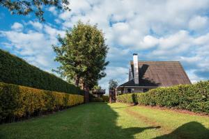 a house with a hedge fence and a yard at The Tea Cottage in Karatina