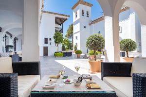 un patio con 2 sofás y una mesa con copas de vino en La Bobadilla, a Royal Hideaway Hotel en Villanueva de Tapia