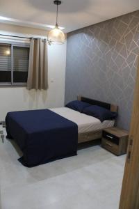 a bedroom with a bed with blue sheets and a window at Oualidia City Centre Cosy Apartment, Free WIFI in Oualidia
