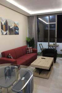 a living room with a red couch and a coffee table at Oualidia City Centre Cosy Apartment, Free WIFI in Oualidia