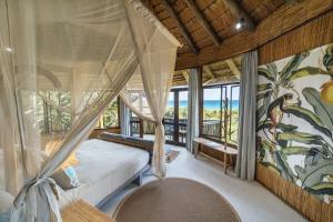 a bedroom with a canopy bed with a view of the ocean at Thonga Beach Lodge in Mabibi