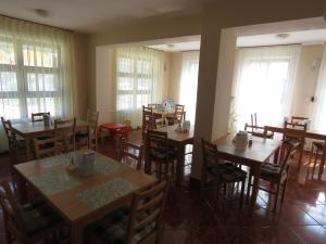 科馬羅姆的住宿－溫泉酒店，餐厅设有木桌、椅子和窗户。