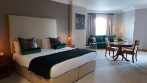 a bedroom with a large bed and a table and chairs at Lady Gregory Hotel, Leisure Club & Beauty Rooms in Gort