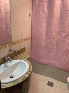 baño con lavabo y cortina de ducha rosa en The Mood House I Dubai Marina en Dubái