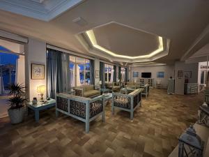 a living room with couches and tables and windows at Alea Mare Hotel in Alinda