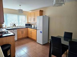 a kitchen with a refrigerator and a table with chairs at Baltic Gem 4 Bedroom Townhouse with free parking in Liverpool