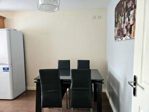 a dining room table with chairs and a refrigerator at Baltic Gem 4 Bedroom Townhouse with free parking in Liverpool