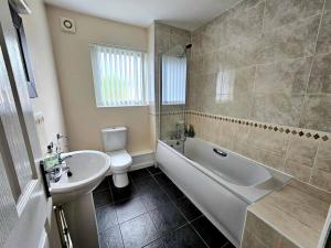 La salle de bains est pourvue d'un lavabo, d'une baignoire et de toilettes. dans l'établissement Baltic Gem 4 Bedroom Townhouse with free parking, à Liverpool