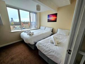 two twin beds in a room with a window at Baltic Townhouse, 4 Bed, Parking - Pass the Keys in Liverpool