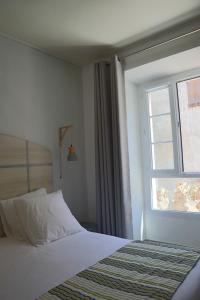 a bedroom with a bed and a window at Le Royal Hôtel Restaurant in Bonifacio